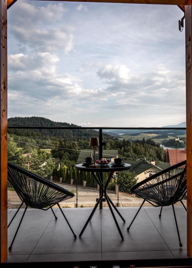 Balkon z dwoma fotelami i widokiem na okoliczne wzgórza